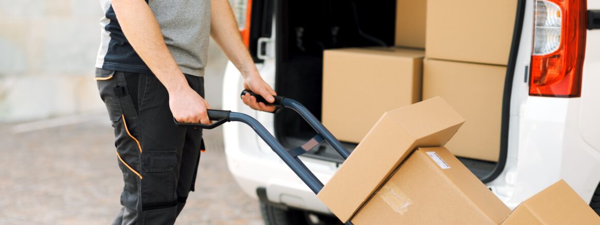 Professional delivery guy pushing a hand truck loaded with packages, express courier and delivery service concept